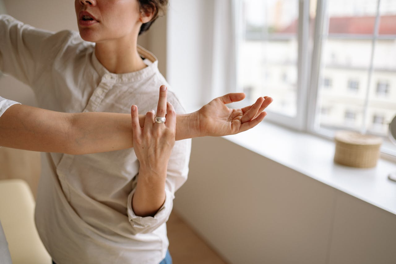 Physical therapist stretches a woman's arm in a sunny room.
